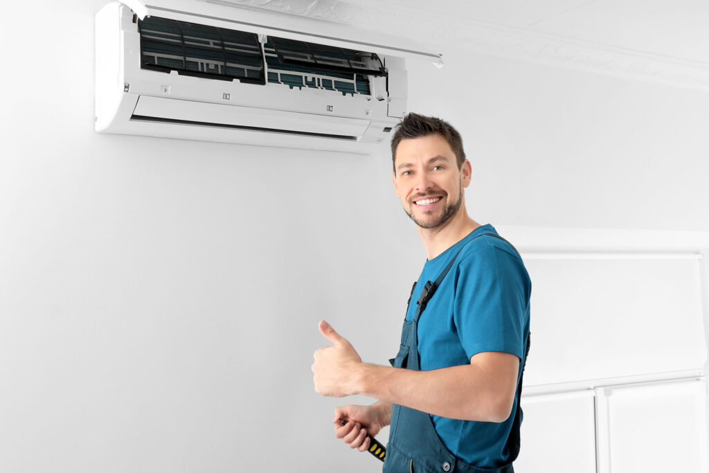 Male technician after successful repair of air conditioner indoo
