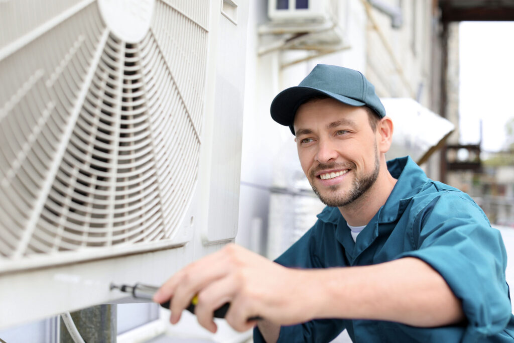 Male technician repairing air conditioner outdoors